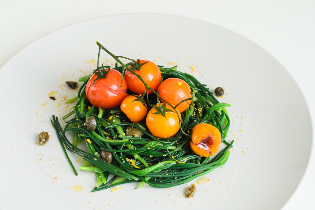 Agretti nest with pan-seared tomatoes on the vine